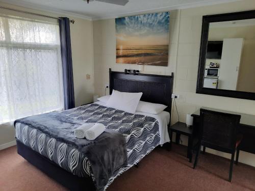 1 dormitorio con 1 cama con 2 toallas en Flying Spur Motel, en Toowoomba