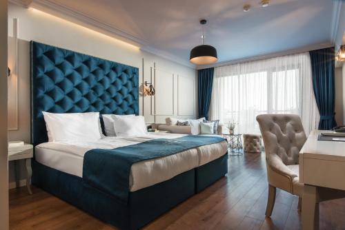 a bedroom with a large bed with a blue headboard at Casa di Fiore SPA and Medical Hotel, Mineral Pools & Private Beach in Kranevo