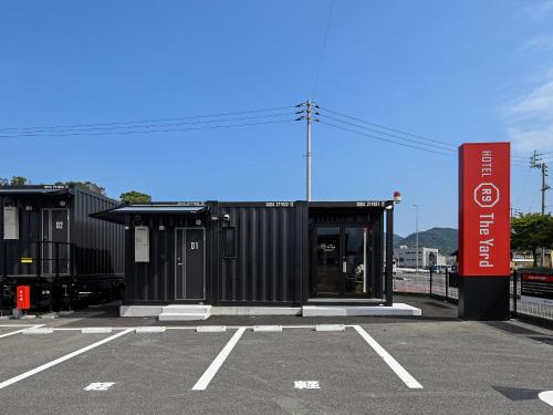 四国中央市にあるHOTEL R9 The Yard 四国中央の駐車場の看板のある黒い建物