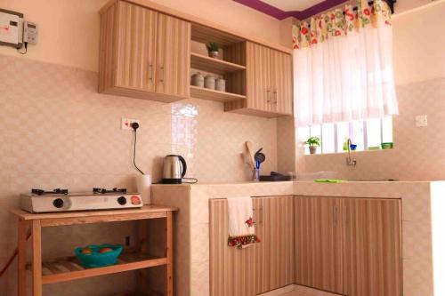 una pequeña cocina con armarios de madera y microondas en Cosy and spacious apartment in Meru, en Meru