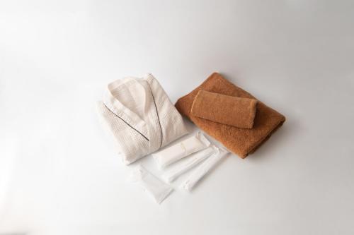 a group of three towels on a white background at HOTEL R9 The Yard Shikokuchuo in Shikokuchuo