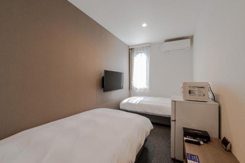 a hotel room with two beds and a television at HOTEL R9 The Yard Shikokuchuo in Shikokuchuo