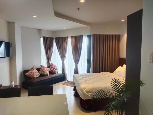 1 dormitorio con 1 cama y 1 sofá en una habitación en Tambuli Residence, en Maribago