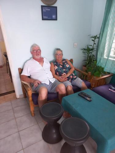duas pessoas mais velhas sentadas num sofá numa sala de estar em Sun n Tan Beach Home stay em Cananor