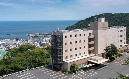 a large white building with the ocean in the background at KAMENOI HOTEL Atami Annex in Atami