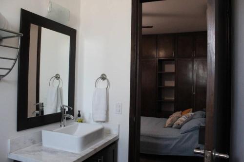 baño con lavabo, espejo y cama en Casa Las Palmas, llena de vida, con alberca. en La Paz