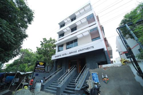 a large white building with stairs in front of it at Majestic Hotel in Madurai
