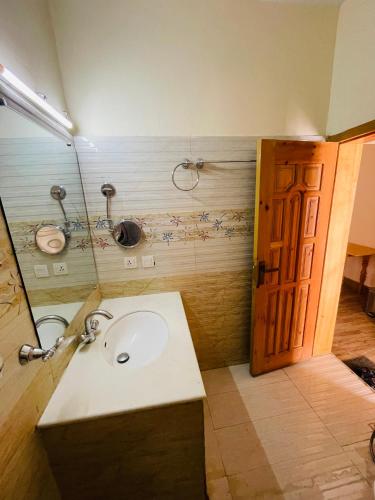 a bathroom with a sink and a mirror and a door at Karakorum View Hotel Karimabad Hunza in Hunza