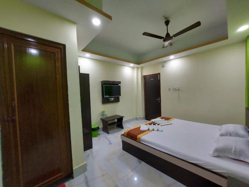 a bedroom with a large bed with a ceiling fan at ICONIC Hotel Digha in Digha