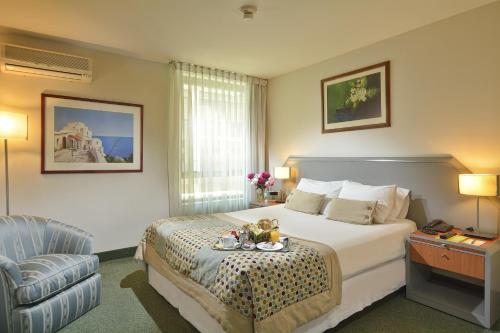 a hotel room with a bed and a chair at Hotel Eurotel El Bosque in Santiago