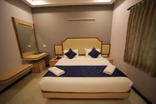 a bedroom with a large bed with blue pillows at Majestic Hotel in Madurai