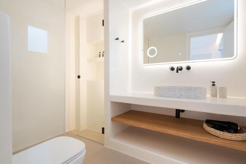 a white bathroom with a sink and a mirror at Citrus Seaside Houses in Plaka