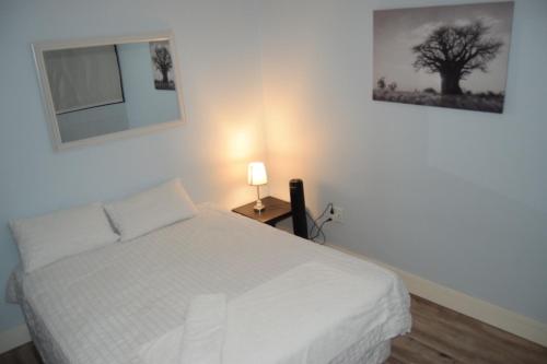 a bedroom with a white bed and a tree on the wall at Scenic Apartment in Windhoek City Centre in Windhoek