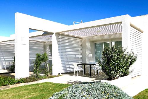 una casa blanca con una mesa en el patio delantero en Resort con piscina a soli 250 mt dalla spiaggia La Pelosa, en Stintino