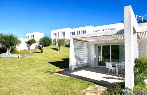 una casa blanca con césped delante en Resort con piscina a soli 250 mt dalla spiaggia La Pelosa, en Stintino