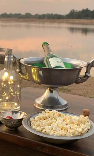 a plate with a bottle of wine in a bucket at Msandile River Lodge in Kakumbi