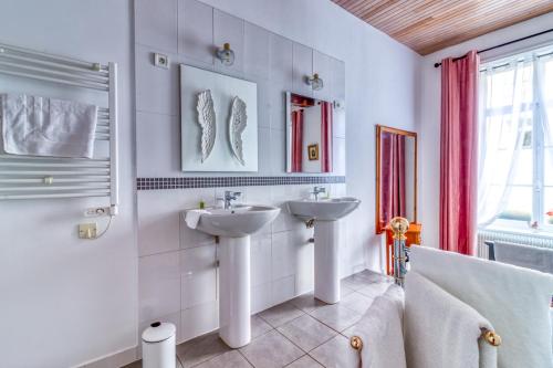 a white bathroom with two sinks and a tub at La Boulonnaise in Boulogne-sur-Mer