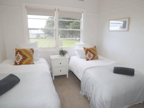 two twin beds in a room with a window at Cosy 3 bedroom cottage with indoor fireplace in Romsey