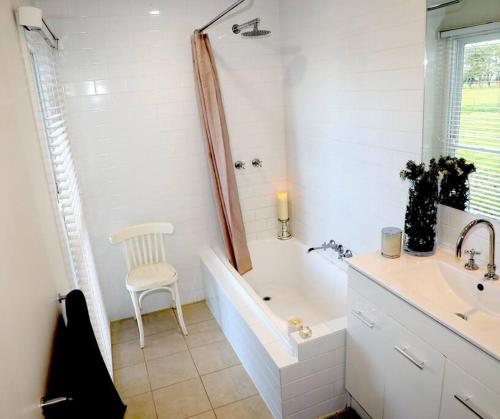 Baño blanco con bañera y lavamanos en Cosy 3 bedroom cottage with indoor fireplace, en Romsey
