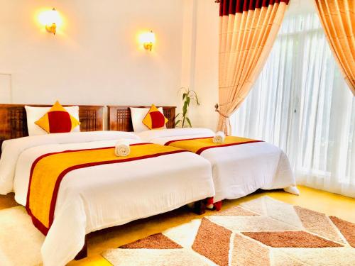 1 dormitorio con 2 camas y ventana grande en Seeming Lodge, en Nuwara Eliya