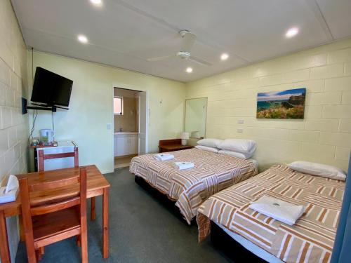 a room with two beds and a table and a tv at Golden Grain Motel in Pittsworth