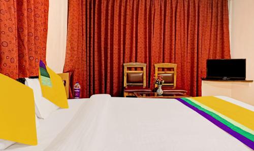 a bedroom with a white bed and two chairs at Itsy Hotels Crown Inn in Pune
