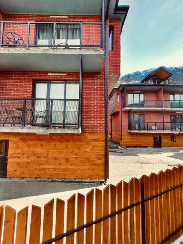 a red brick building with a fence in front of it at Kazbegi Luxury Apartment in Stepantsminda