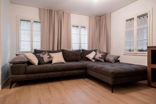 a brown couch in a living room with windows at House Leska in Kranjska Gora