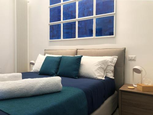 un letto con cuscini blu e bianchi e una finestra di Lily Apartment Napoli a Napoli