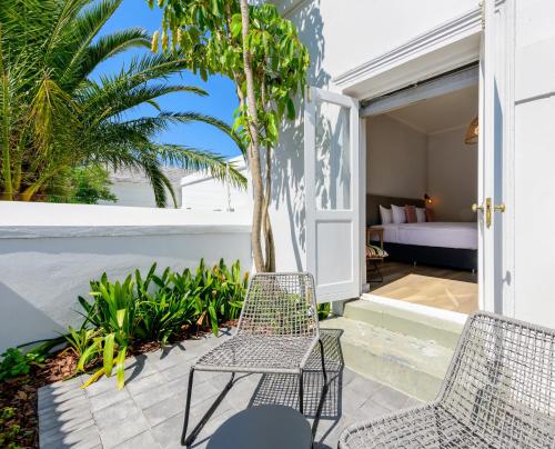 a patio with two chairs and a bed at iGadi House Boutique Hotel in Cape Town
