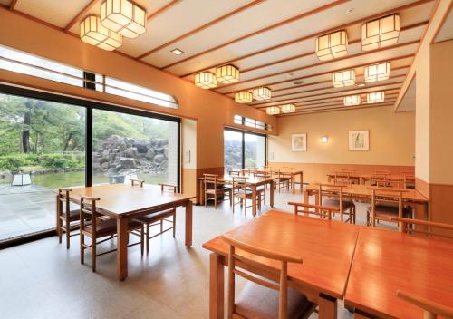 a dining room with tables and chairs and large windows at Kamogawa Grand Tower in Kamogawa