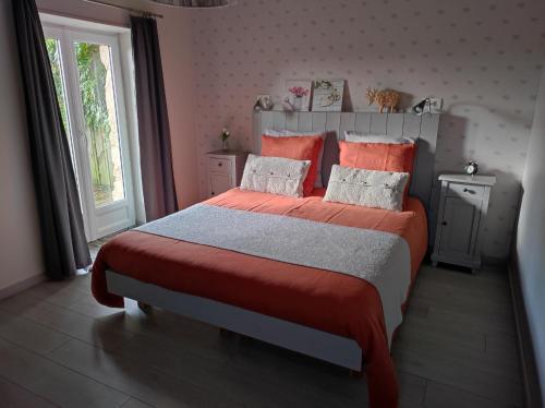 a bedroom with a large bed with orange sheets and pillows at Gîte Ti-Maes in Briec
