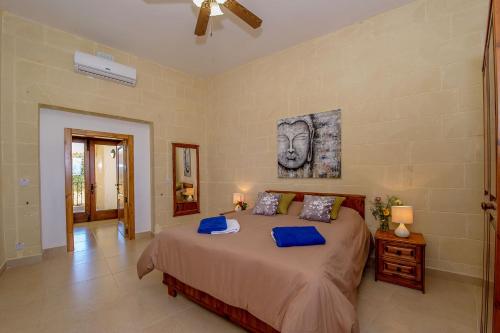 a bedroom with a large bed with blue pillows at The Harbour Holiday Home in Għajnsielem