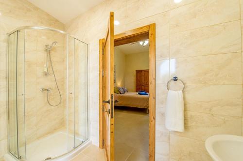 y baño con ducha acristalada y lavamanos. en The Harbour Holiday Home en Għajnsielem