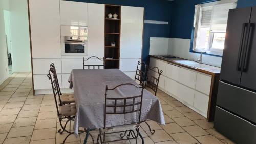 une cuisine avec une table, des chaises et un réfrigérateur dans l'établissement Maison familiale avec jardin clos et barbecue, au Puy-en-Velay