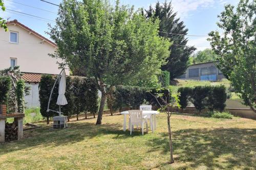 einen Garten mit einem Tisch, einem Baum und einem Sonnenschirm in der Unterkunft Maison familiale avec jardin clos et barbecue in Le Puy en Velay