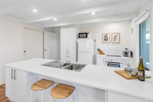 Una cocina blanca con fregadero y refrigerador. en Dromana Beach Holiday House *3 minutes to the sand, en Safety Beach