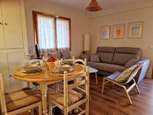 a living room with a table and a couch at ESQUÍ PIRINEO ARAGONÉS APARTAMENTO EL JUNCARAL Wifi in Villanúa