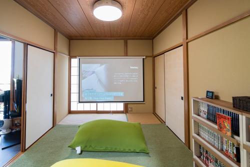 Habitación con pantalla de proyector y sofá verde en スイートヴィラ オーシャンテラスAtami, en Atami