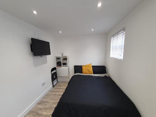 a bedroom with a black bed and a tv at The Suite in Grays Thurrock