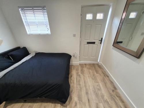 a bedroom with a bed and a mirror and a door at The Suite in Grays Thurrock