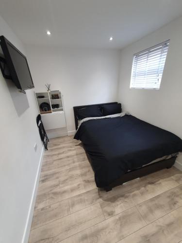 a bedroom with a black bed and a wooden floor at The Suite in Grays Thurrock