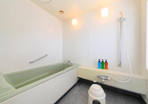 a bathroom with a bath tub and a toilet at Kamogawa Grand Tower in Kamogawa