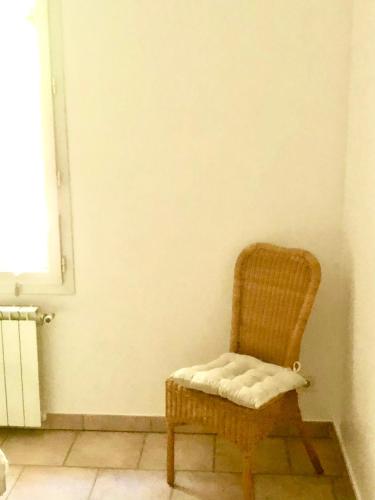 a wicker chair sitting in a corner of a room at Domaine Plan des Devens in Roussillon