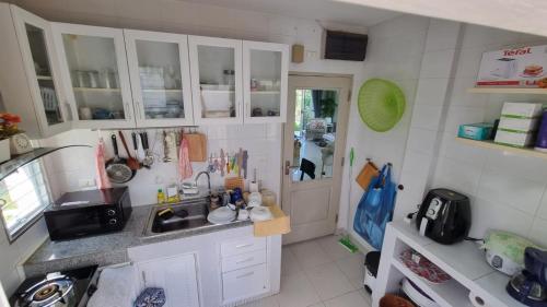 a small kitchen with white cabinets and a sink at Cosy House in Chiangmai in Ban Rong O