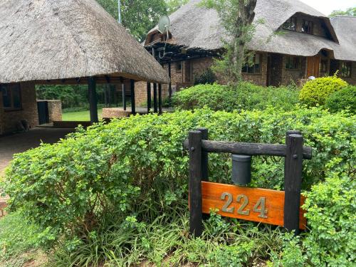 een houten bank voor een huis met een bord bij Kruger Park Lodge, Kubu Lodge 224 in Hazyview