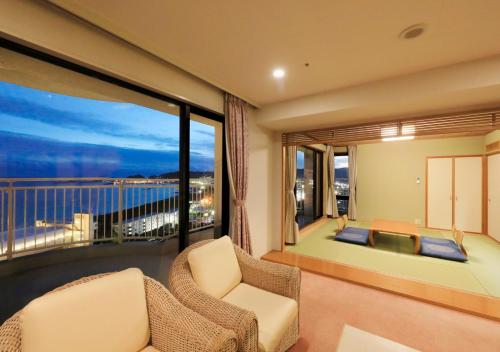 a living room with a balcony with a view of the ocean at Kamogawa Grand Tower in Kamogawa