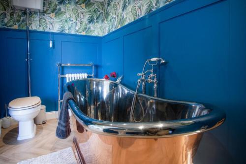 a tub in a bathroom with blue walls and a toilet at The Langland bay look out in Swansea