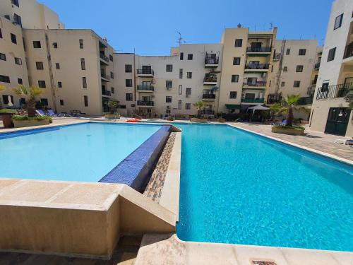 a swimming pool in front of some apartment buildings at Pretty 2 bedroom Apartment with shared Pool in St. Paul's Bay