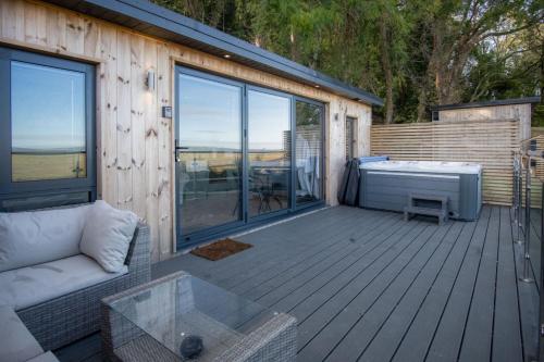 a wooden deck with a couch and a hot tub at The Langland bay look out in Swansea